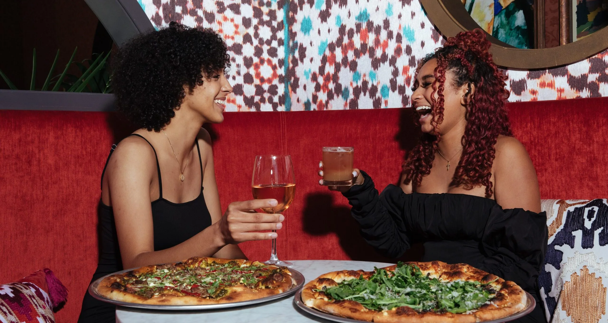 Two women laughing, eating and drinking