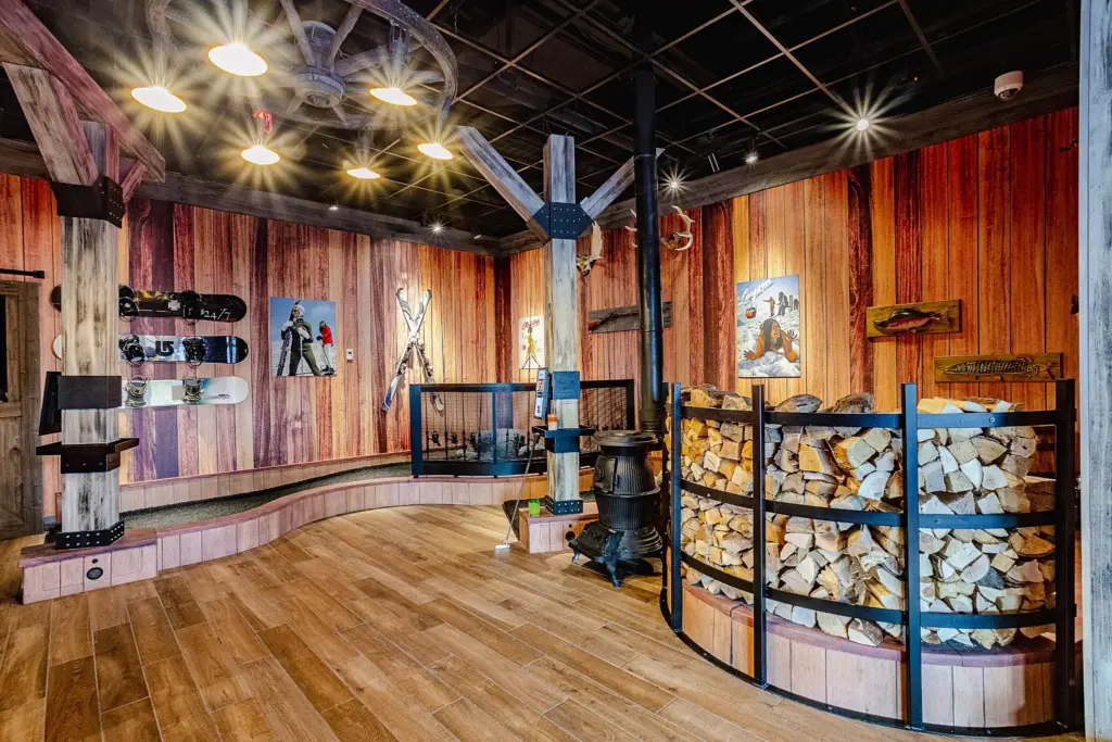 Wide view of the Lodge Course at Puttery Miami with ski and snowboard displays, rustic timber beams, mountain scenery, and winter-themed putting lanes.