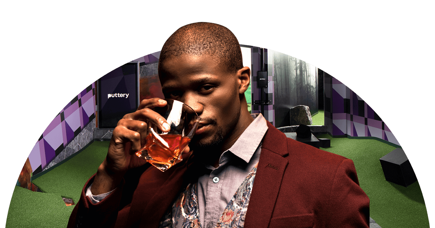 Man sipping whiskey in front of optical illusion putt putt mini golf course at Puttery