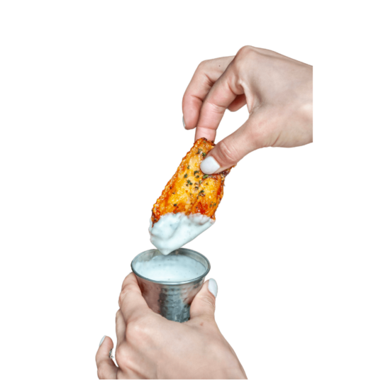 Close-up of a hand dipping a crispy chicken wing into a bowl of creamy ranch dressing at Puttery.