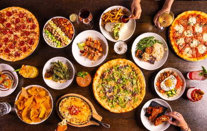 Overhead spread of Puttery chef-driven food, pizza, appetizers, salads and cocktails for group events